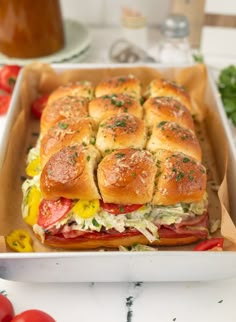 a sandwich in a box with tomatoes and other toppings on the table next to some ketchup