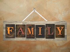 the word family written in wooden letterpresss hanging on a wall with an orange background