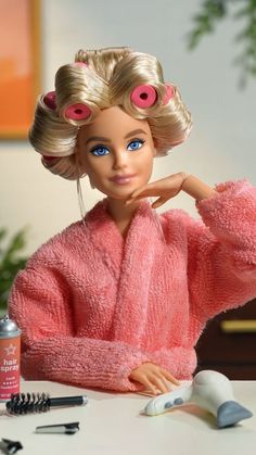 a barbie doll sitting at a table with hair dryers and combs on it