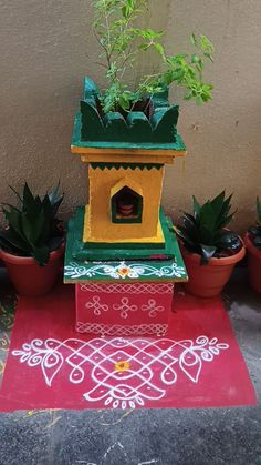 there is a birdhouse with plants in it on the ground next to potted plants