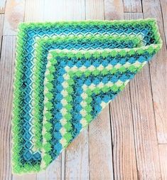 three green and blue crocheted placemats sitting on top of a wooden floor