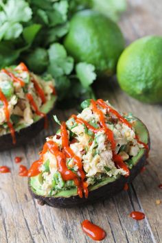 avocado stuffed with chicken salad and dressing on wooden table next to other food items