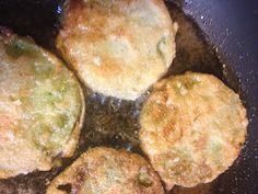 four fried food items cooking in a frying pan