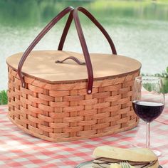 a picnic basket with a glass of wine and cheese on the table next to it