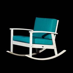 a white rocking chair with blue cushions against a black background