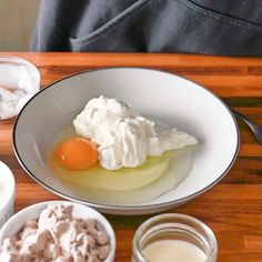 an egg is sitting in a bowl with whipped cream and other ingredients next to it