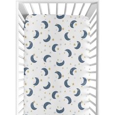 a white crib with stars and crescents on the sheets in front of it