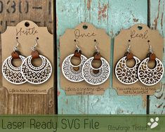 three pairs of laser - cut wood earrings are displayed in front of a wooden background