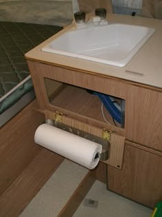 a bathroom with a sink and toilet paper on the floor next to a wooden cabinet