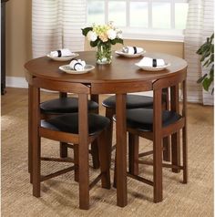 a wooden table with four chairs and a vase filled with flowers on top of it