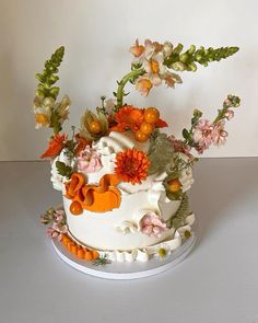 a white cake with orange and pink flowers on it's side, sitting on a table