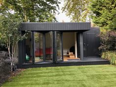 a small black building sitting on top of a lush green field