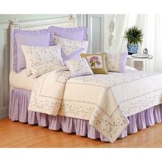 a bed with purple ruffled bedspread and pillows