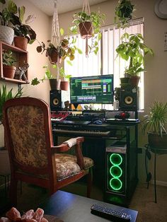 a living room filled with plants next to a computer keyboard and monitor on top of a wooden desk