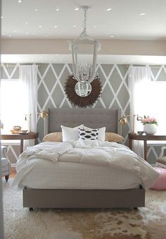 a bedroom with a bed, chandelier and two tables in front of it