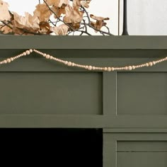 a close up of a fire place with leaves on the mantle and wood bead garland