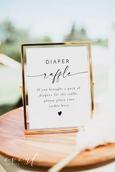 a sign that says diaper raffle on top of a wooden table with feathers