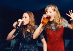 two young women drinking beer and posing for the camera