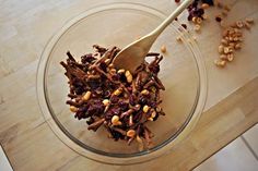 a glass bowl filled with nuts and raisins on top of a wooden table