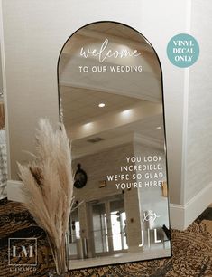 a mirror with the words welcome to our wedding written on it and a feather in front