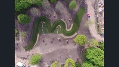 an aerial view of a park with trees and people walking on the path in it