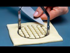 a person using a pair of scissor to cut dough into small balls with white icing