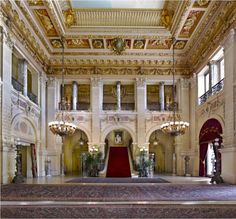 an ornately decorated hall with chandeliers and red carpet