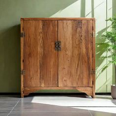 a wooden cabinet sitting on top of a tiled floor next to a potted plant