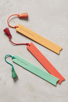 three different colored bookmarks with tassels on each one and an orange string attached to them