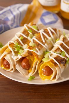 hotdogs wrapped in tortilla wrappers on a plate with mustard and green onions