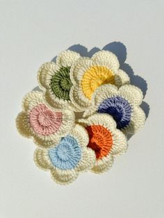 small crocheted flowers on a white surface with one flower in the center and four petals at the bottom