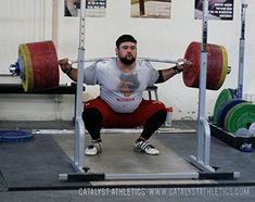 a man squats while holding two barbells in front of his head and shoulders