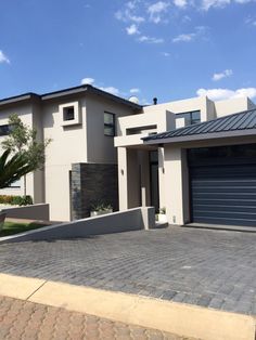 a house with a large driveway and two garages in front of it on a sunny day