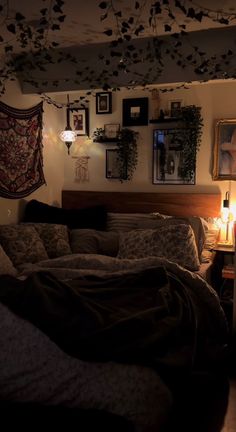 an unmade bed in a dimly lit room with pictures on the wall above it