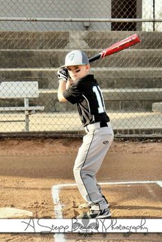 a young boy holding a baseball bat on top of a field