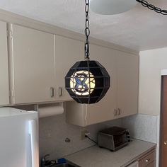 a kitchen with white cabinets and a stained glass light fixture hanging from the ceiling above it