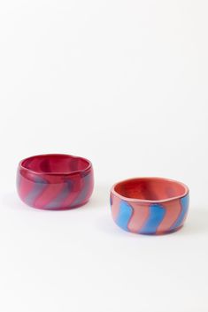 two red and blue bowls sitting next to each other on a white surface with no one in it