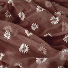 the fabric has flowers on it and is brown with white trimmings, as well as sheer tulle