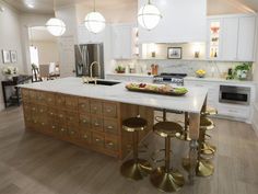 a kitchen with white cabinets and gold stools next to an island in the middle