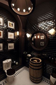 a bathroom with black and white tile flooring and wooden barrel style sink, toilet and mirror