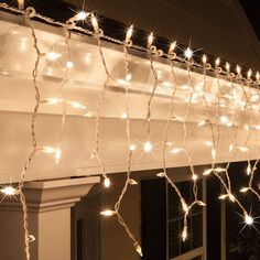 white lights are strung on the outside of a house's window sill in front of an awning