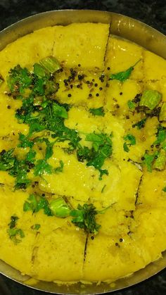 a pan filled with food sitting on top of a stove covered in cheese and greens