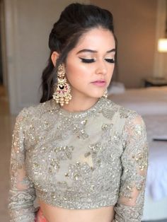 a woman with long hair wearing a silver dress and gold earrings, looking down at her face