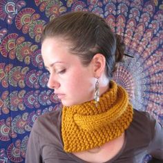 a woman wearing a yellow knitted cowl neckwarf in front of a colorful background