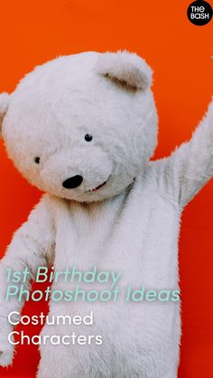 a white teddy bear standing in front of an orange wall with its arms up and paw raised