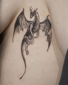 a black and white photo of a dragon tattoo on the side of a woman's stomach