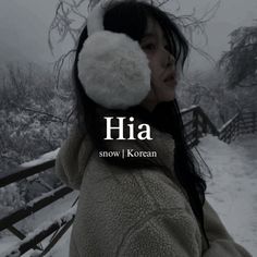 a woman wearing ear muffs standing in front of snow covered trees with the words hia above her head