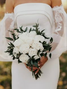 a bride holding a bouquet of white roses