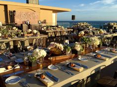 an outdoor dining area overlooking the ocean with tables and chairs set up for a meal