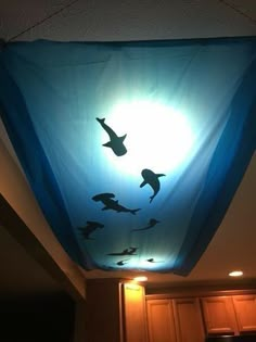 a light that is on the ceiling above a kitchen counter with some birds flying around it